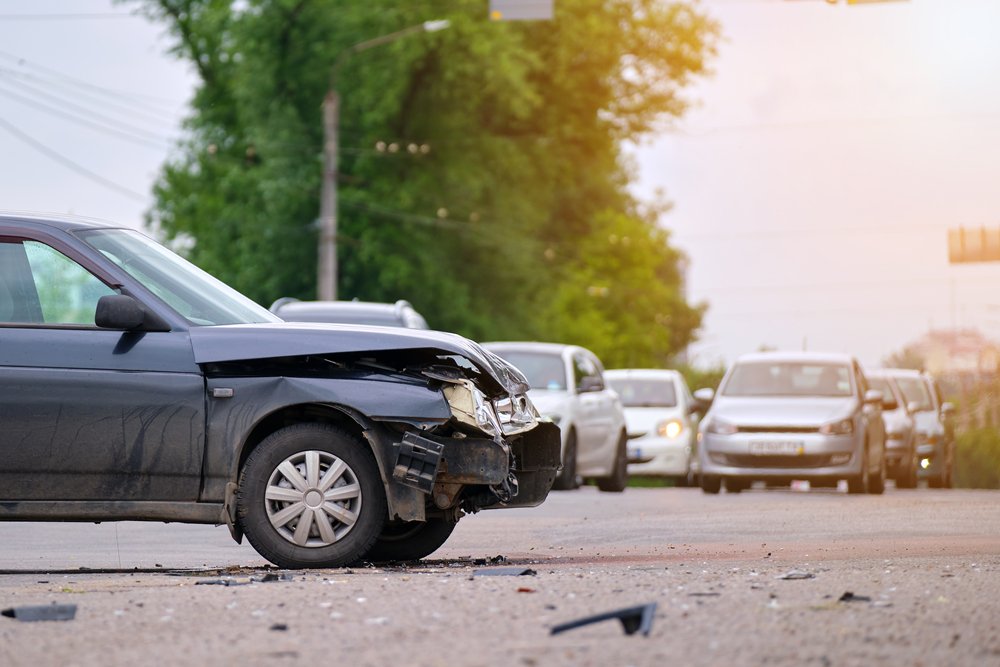 Car with a crushed front end sitting in traffic after an accident