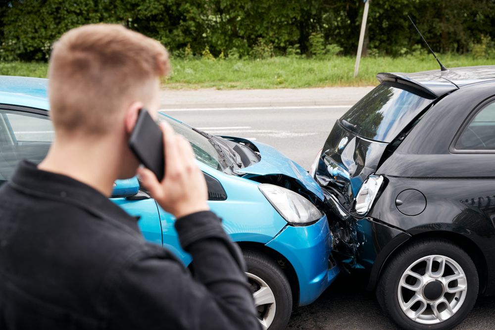 Man on the phone reporting a crash after a two-car collision