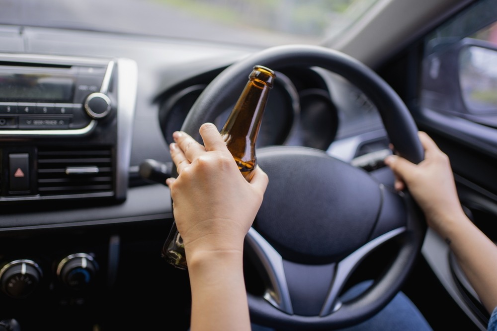 Driver holding a beer bottle while gripping the steering wheel
