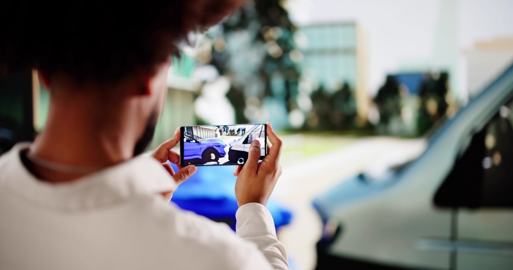 Person photographing car accident damage on a smartphone for insurance documentation