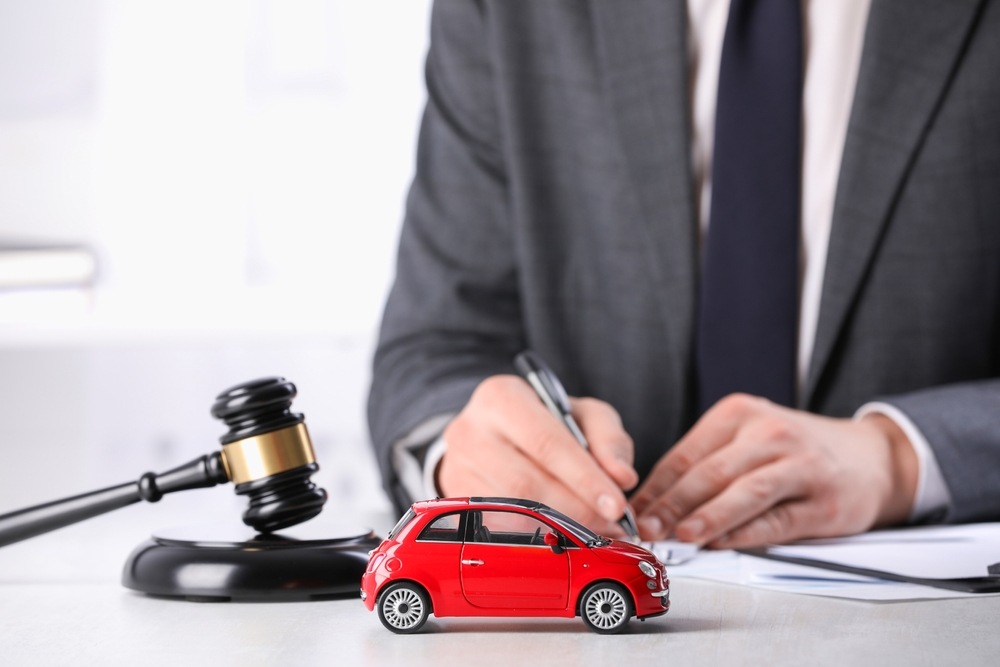 Attorney signing documents beside a toy car and gavel, representing a Georgia auto accident claim