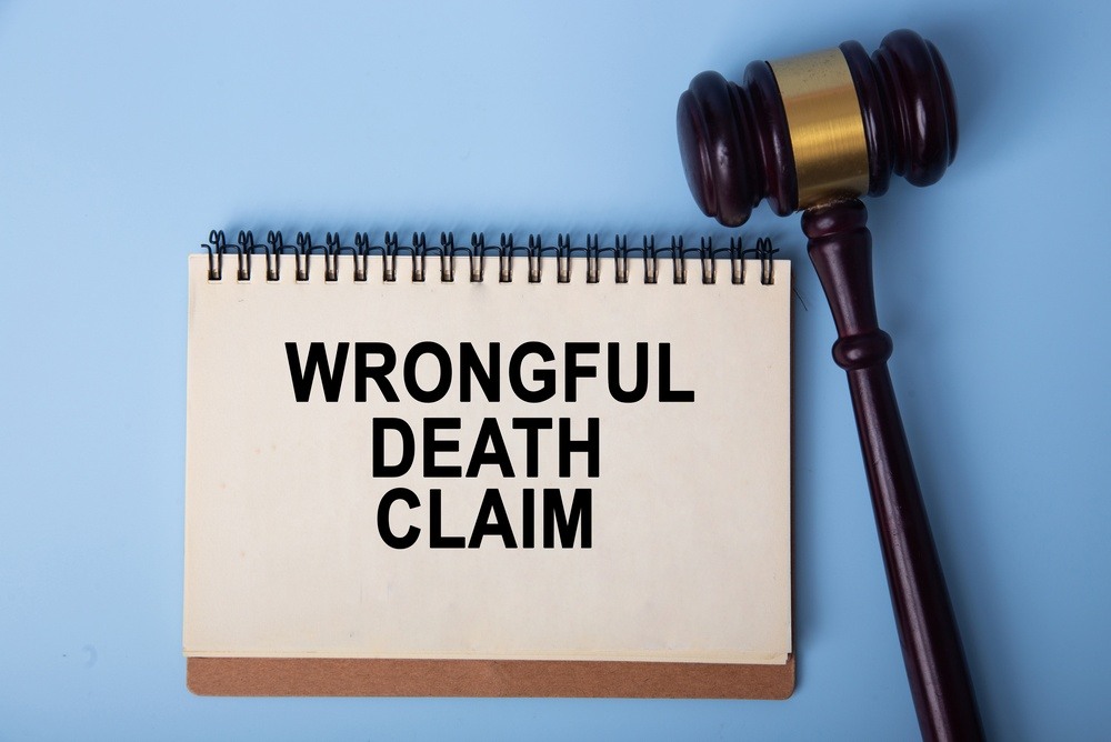 Notepad reading "Wrongful Death Claim" next to a judge's gavel