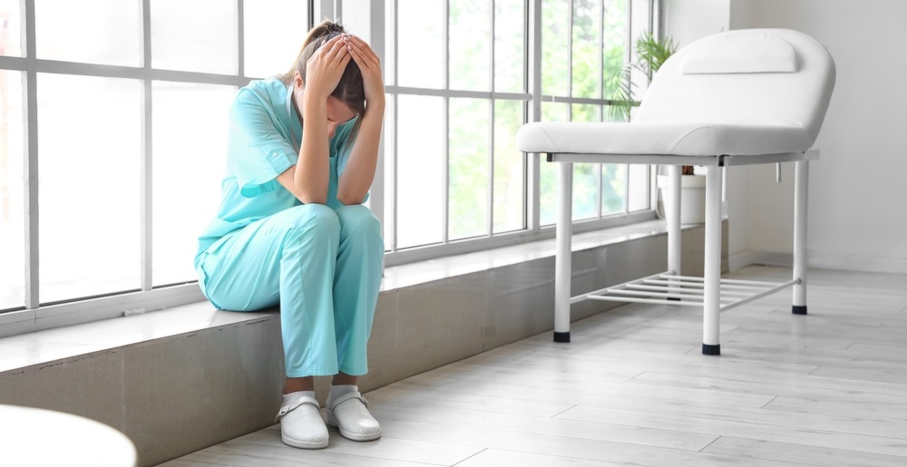 Distressed nurse sitting with her head in her hands, reflecting a medical error that can lead to a wrongful death claim