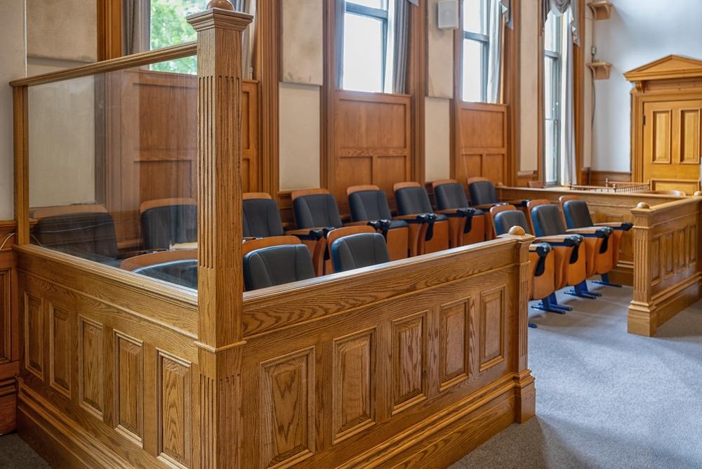 Empty jury box with rows of upholstered chairs inside a wood-paneled courtroom
