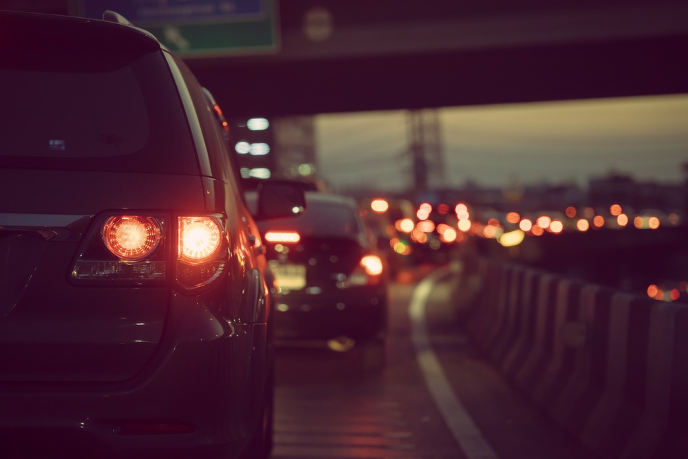 Line of cars with red brake lights glowing in heavy traffic on a highway at dusk